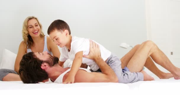 Familia jugando juntos en una cama — Vídeo de stock