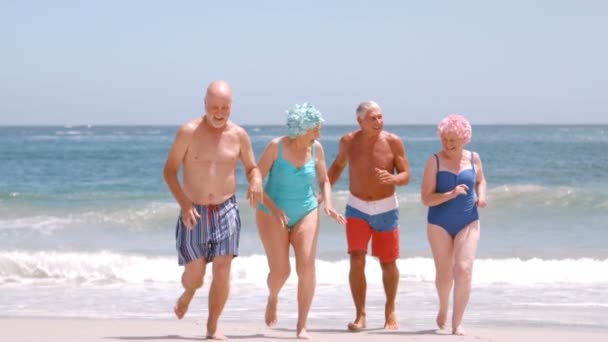 Зрелая группа людей бежит по пляжу — стоковое видео