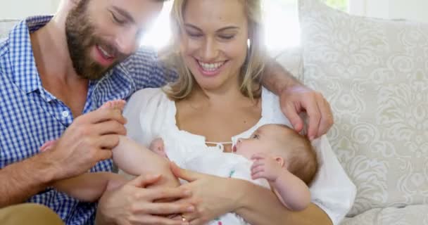 Couple assis sur un canapé tenant leur bébé — Video