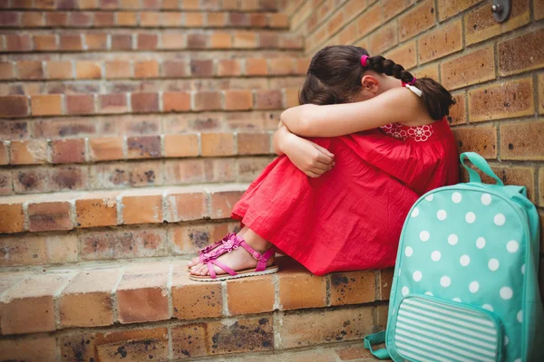 Triest schoolmeisje met hoofd in haar benen — Stockfoto