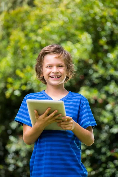 Un petit garçon sourit avec une tablette — Photo