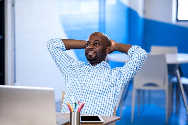 Businessman with hands behind hand resting at desk — Stock Photo, Image