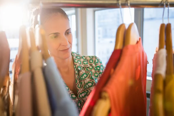 Mujer seleccionando una prenda mientras compra ropa — Foto de Stock