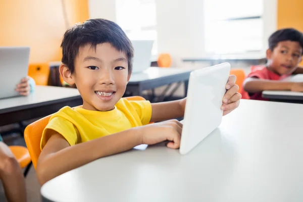 Niño feliz posando con la tableta en el escritorio — Foto de Stock