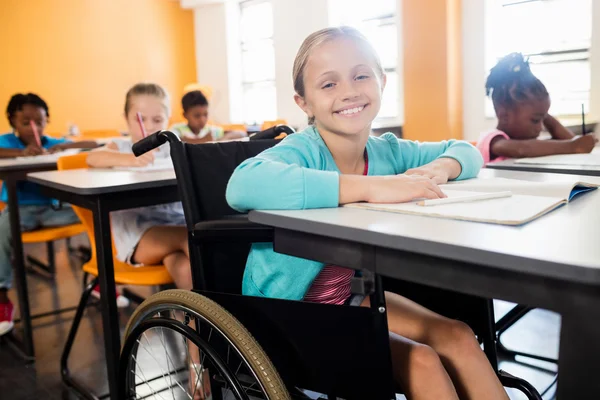 Smiling pupil in wheel chair posing for camera at desk — Stock Photo, Image