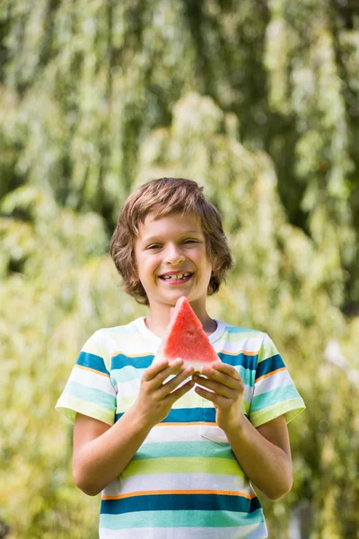 En liten pojke ler med en vattenmelon — Stockfoto