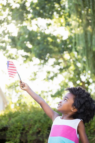 Una niña pequeña sostiene una bandera americana en el aire — Foto de Stock
