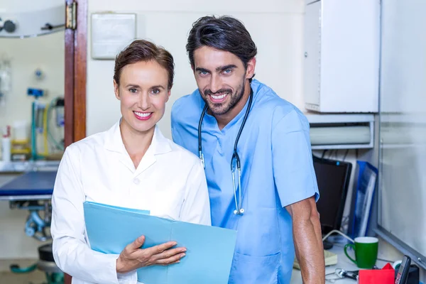 Porträt zweier Tierärzte, die lächeln und Dokumente studieren — Stockfoto