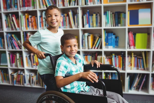 Хлопчик штовхає інвалідне крісло — стокове фото