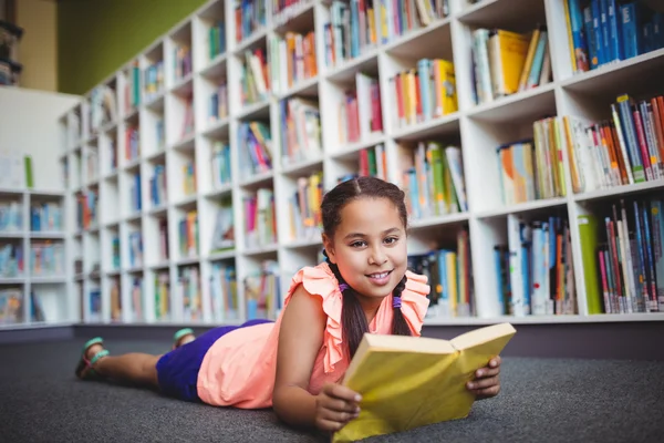 Menina deitada com um livro e olhando para a câmera — Fotografia de Stock