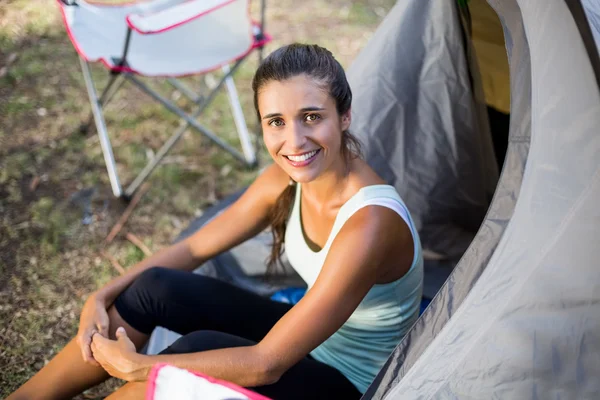 Femme souriante et assise sur une tente — Photo