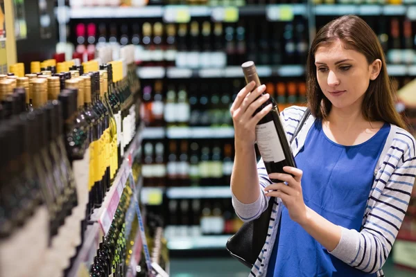 Woman looking at wine bottle — Stock Photo, Image