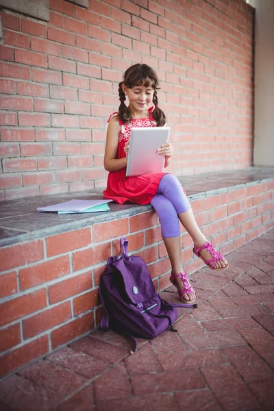 Школярка дивиться на свій цифровий планшет — стокове фото