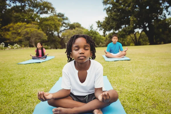 Giovane ragazzo che fa yoga con altri bambini — Foto Stock