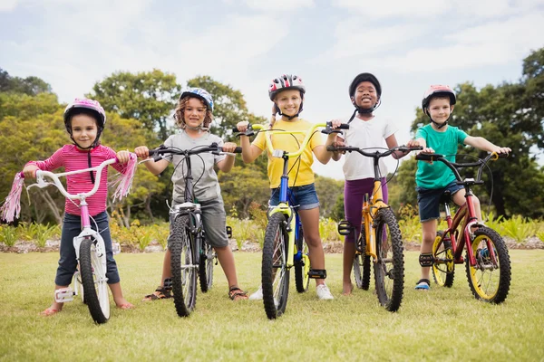 Crianças felizes usando capacete e posando em sua bicicleta — Fotografia de Stock