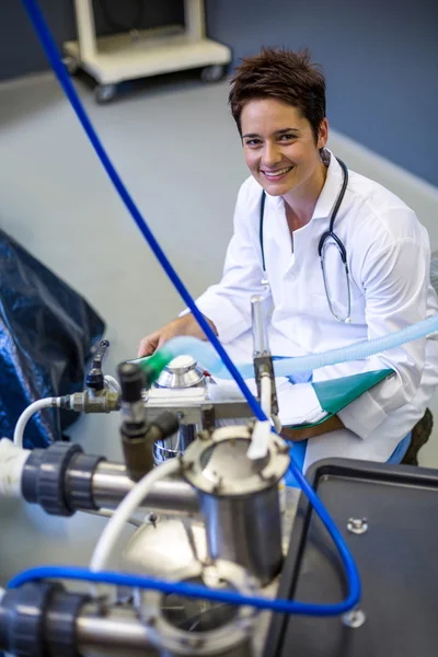 Mulher veterinária sorrindo e posando atrás da máquina médica — Fotografia de Stock