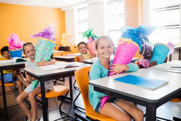 Щасливі учні сидять за своїм столом з подарунковими коробками — стокове фото