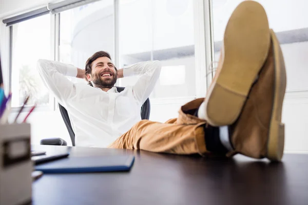 Un homme souriant se relaxant au bureau — Photo