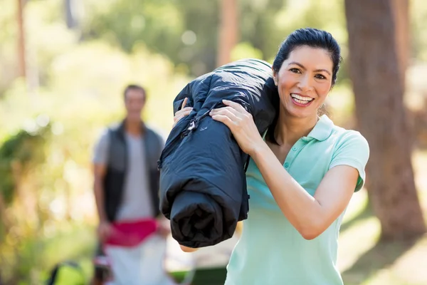 Женщина улыбается и держит спальный мешок — стоковое фото