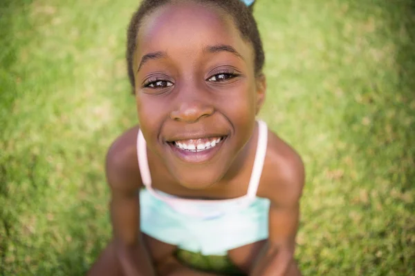 Linda chica de raza mixta sonriendo y sentado en la hierba —  Fotos de Stock
