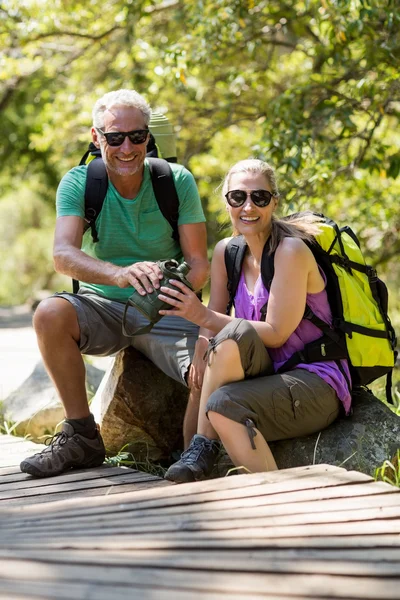 Casal sorrindo e fazendo uma pausa durante uma caminhada — Fotografia de Stock