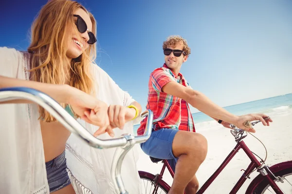 Par poserar med cykel på stranden — Stockfoto