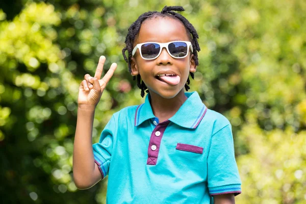 Niño con la lengua extendida usando gafas de sol — Foto de Stock