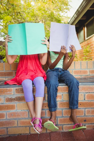 Két lány hided mögött a copybook — Stock Fotó