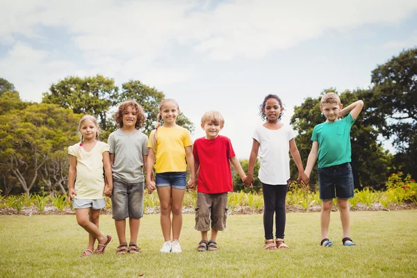 Enfants heureux souriant et tenant par les mains — Photo