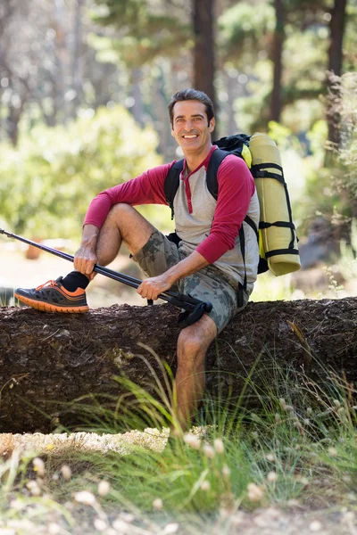 Man hiker smiling and sitting on a tree — Stock Photo, Image