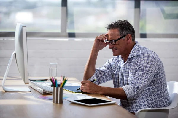 Sidovy av en affärsman som arbetar vid skrivbord — Stockfoto