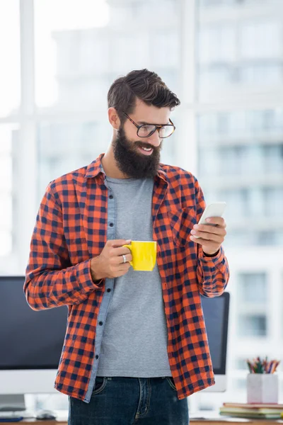 Hipster using smartphone and drinking coffee — Stock Photo, Image
