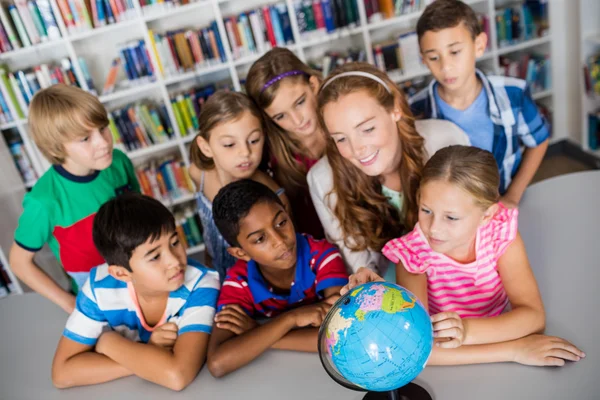 Leraar en leerlingen kijken naar een globe — Stockfoto