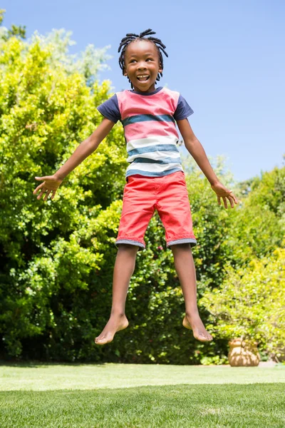 Um menino sorrindo está pulando — Fotografia de Stock