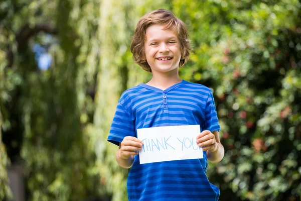 Mignon garçon souriant et tenant un message — Photo