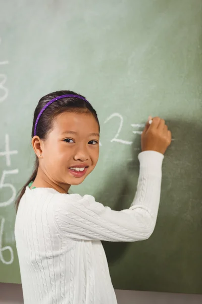 Girl writing with chalk on blackboard — Stock Photo, Image