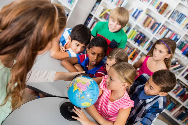 Вчитель і учні дивляться на глобус — стокове фото