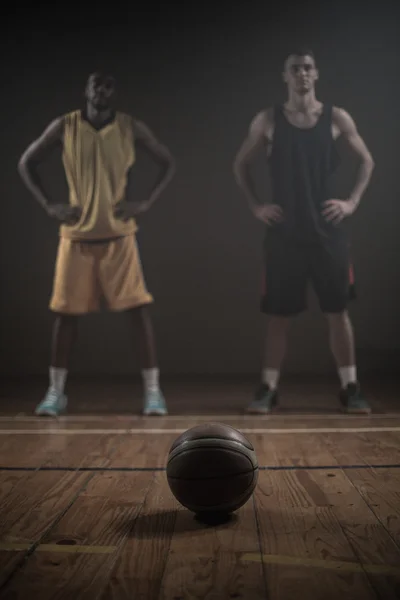 Pemain basket berpose dengan tangan di pinggul di belakang bola — Stok Foto