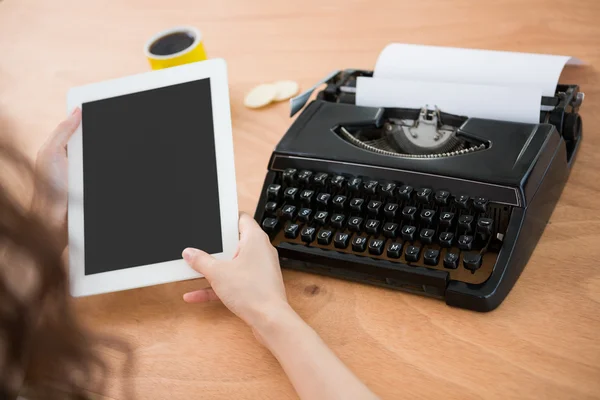 Hipster woman using a tablet beside her typewriter — Stock Photo, Image