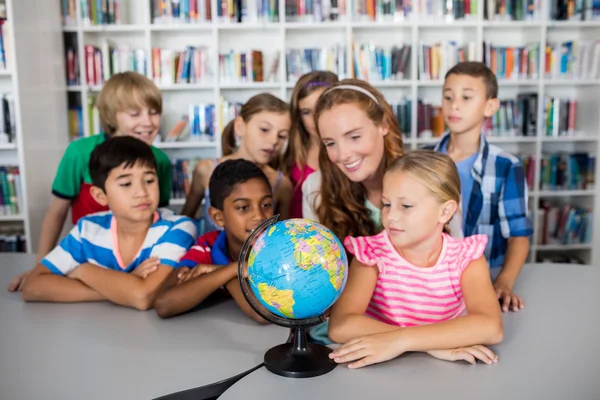 Enseignant et élèves regardant un globe terrestre — Photo