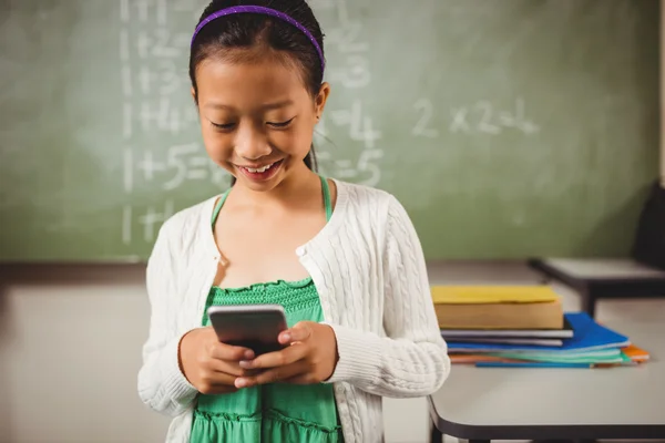 Mosolyogva, miközben egy smartphone iskoláslány — Stock Fotó