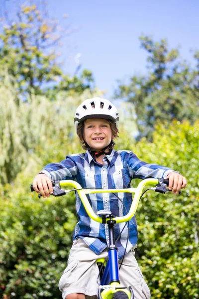 Retrato de niño lindo sonriendo y posando en su bicicleta — Foto de Stock