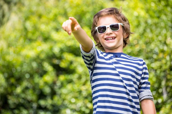 Portrait de garçon mignon avec des lunettes de soleil pointant quelque chose — Photo