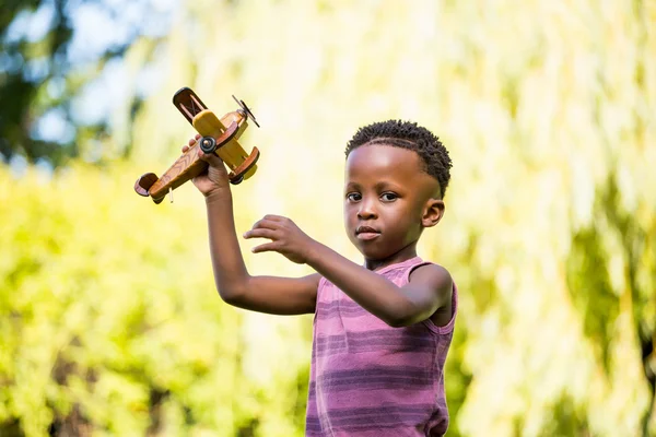 Lindo chico de raza mixta jugando con un pequeño avión — Foto de Stock