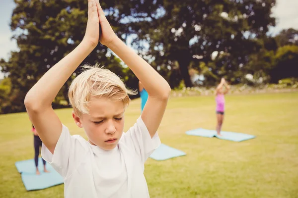 Ung dreng gør yoga med andre børn - Stock-foto