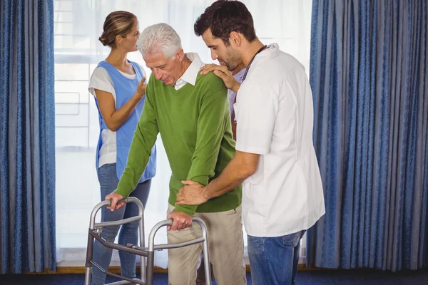 Медсестра допомагає літнім людям ходити з ходунком — стокове фото