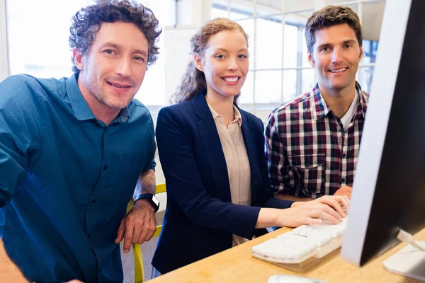 Empresarios sonriendo y posando frente a una computadora — Foto de Stock