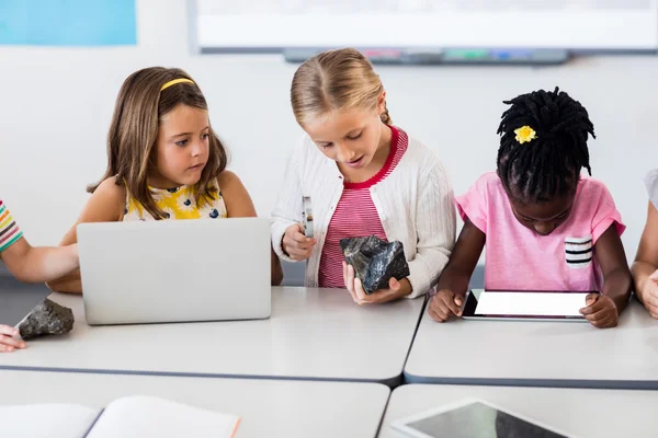 Leerling kijken naar rock met Vergrootglas en klasgenoten met behulp van — Stockfoto