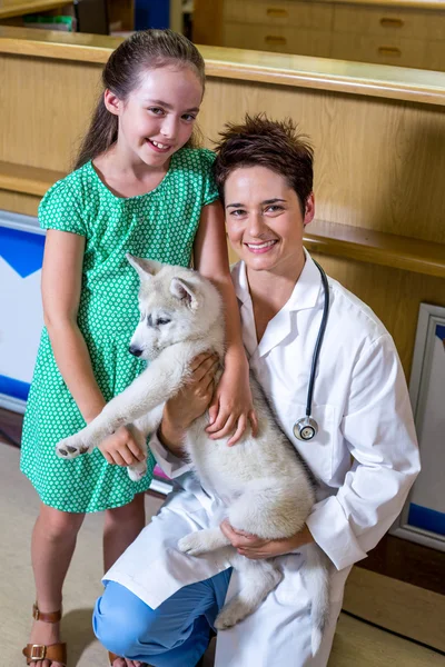 Portrait de petite fille et femme vétérinaire tenant un chiot mignon — Photo