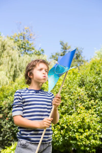 Porträtt av söta pojken blåser på en väderkvarn — Stockfoto